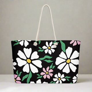 Black tote bag with pink and white flower design, styled for weekend travel or everyday use
