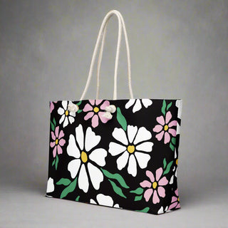 Side view of large floral print weekender tote bag featuring daisy pattern on black background