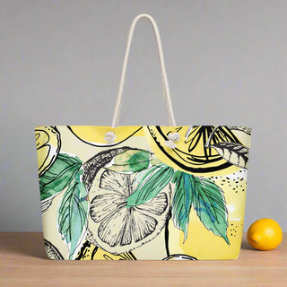Front view of oversized weekender tote with lemon and leaf print on yellow background, rope handles
