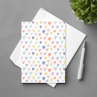 Pastel hearts greeting card with white envelope and pen