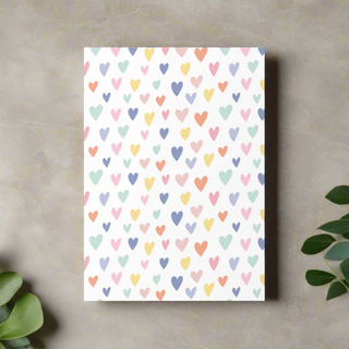 Flat lay of pastel multicolor hearts greeting card on marble background with greenery