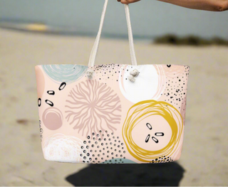Abstract print tote bag with rope handles held by woman at the beach