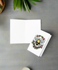 Eco-friendly greeting card featuring a bee inside a floral wreath on premium paperboard on counter