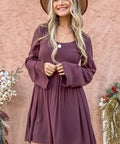 Woman wearing long sleeve babydoll dress with button front and bell sleeves