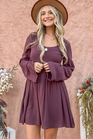 Woman wearing long sleeve babydoll dress with button front and bell sleeves