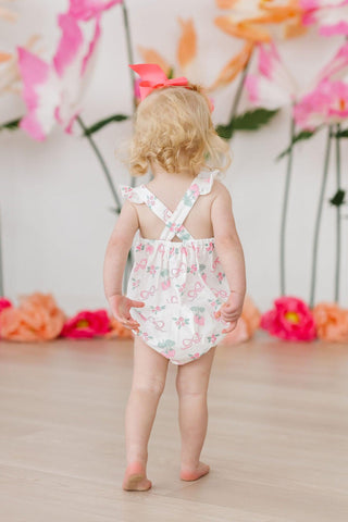 Baby girl wearing pink berry & bow print ruffle cross-back romper, back view