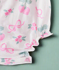 Pink berry & bow print baby romper with ruffle straps, flat lay front