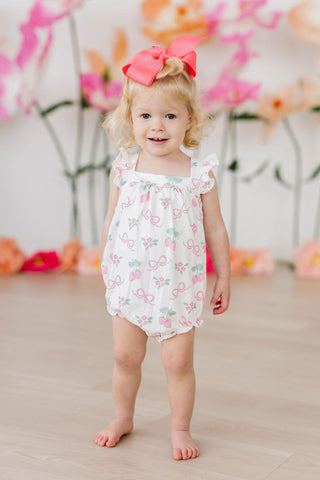 Baby girl wearing pink berry & bow print ruffle cross-back romper, front view