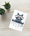 Flat lay of raccoon greeting card with envelope and small plant props