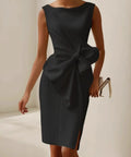 woman wearing black cocktail midi dress with oversized bow detail and side slit