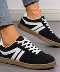 Black lace-up sneakers with white contrast detailing styled with cropped denim jeans for everyday casual fashion.