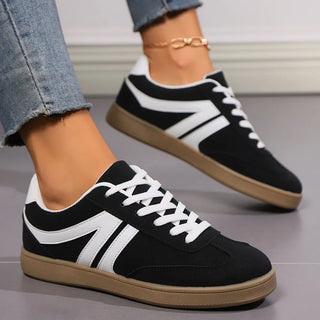 Black lace-up sneakers with white contrast detailing styled with cropped denim jeans for everyday casual fashion.