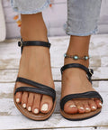 Black comfort flat sandals with minimalist strappy design and adjustable ankle closure for everyday style.