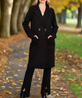 Woman wearing black double breasted coat with lapel collar, hands in pockets
