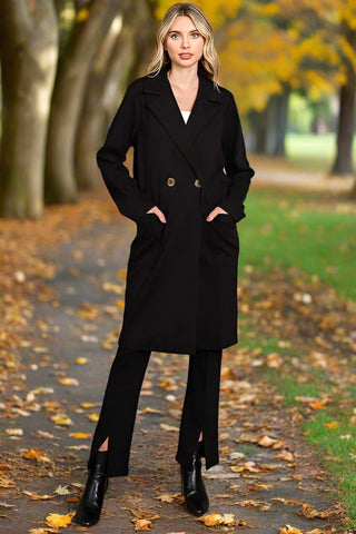 Woman wearing black double breasted coat with lapel collar, hands in pockets