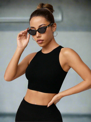 Woman styled in black seamless cropped tank and sunglasses