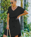 Woman in black v-neck belted A-line dress outdoors