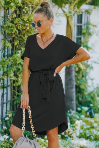 Woman in black v-neck belted A-line dress outdoors