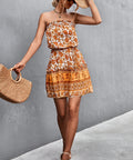 Woman wearing boho print strapless mini dress with straw hat and bag