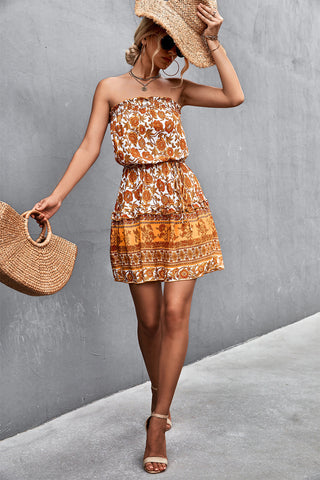 Woman wearing boho print strapless mini dress with straw hat and bag