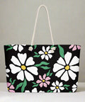 Black tote bag with pink and white flower design, styled for weekend travel or everyday use