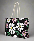 Side view of large floral print weekender tote bag featuring daisy pattern on black background
