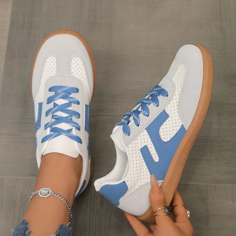Woman holding blue and white colorblock lace-up sneakers with gum sole