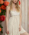 Woman wearing cream floral mini dress with ruffle hem and spaghetti straps