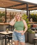 Curvy model in green cropped tank top with denim shorts