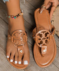 Woman wearing brown cutout slip-on sandals with round medallion design