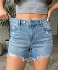 Women's distressed denim shorts with a raw hem and high-rise fit styled for casual summer outfits.