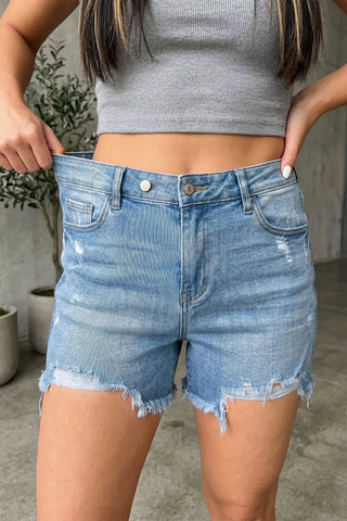Women's distressed denim shorts with a raw hem and high-rise fit styled for casual summer outfits.