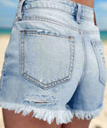 Back view of high-waisted light wash denim shorts with raw edge