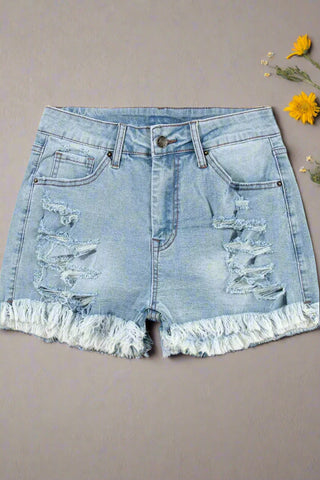 Flat lay of distressed jean shorts with raw hem and front rips 