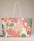 Top view of pink and green floral weekender tote bag styled with plant background