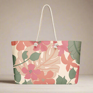 Top view of pink and green floral weekender tote bag styled with plant background