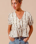 Woman wearing a floral tie front smocked hem blouse styled with denim shorts