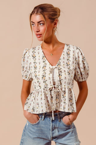 Woman wearing a floral tie front smocked hem blouse styled with denim shorts