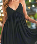 Woman posing in flowy black plunge mini sun dress