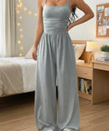 Light gray spaghetti strap wide leg jumpsuit paired with casual accessories for spring and summer style.
