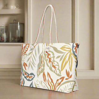Back angle of fall weekender tote with botanical leaf pattern in orange, olive, and tan