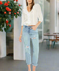 Woman wearing relaxed light wash distressed boyfriend jeans and white blouse