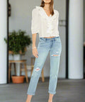 Standing front view of woman in light wash relaxed fit ripped jeans