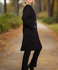 Side view of woman wearing long black trench-style coat