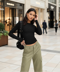 Woman wearing black fitted long sleeve top styled with olive trousers