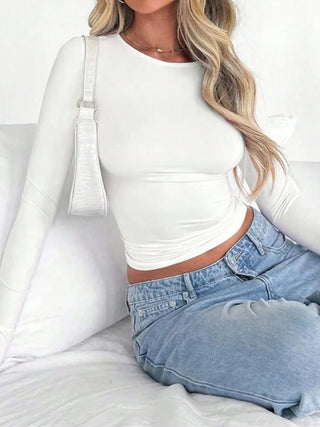 Woman wearing white fitted long sleeve top seated on sofa