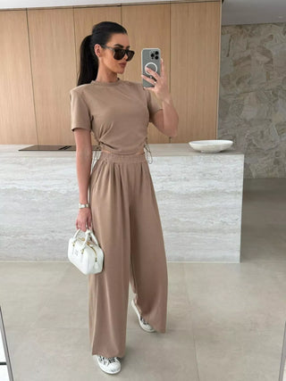 neutral two piece travel outfit featuring adjustable crop top and wide leg pants