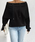 Woman wearing a black off-shoulder drawstring long sleeve top styled with jeans