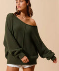 Woman wearing an olive green loose fit exposed seam slouchy bouclé sweater styled with shorts