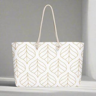 Gold leaf print weekender tote placed on white surface